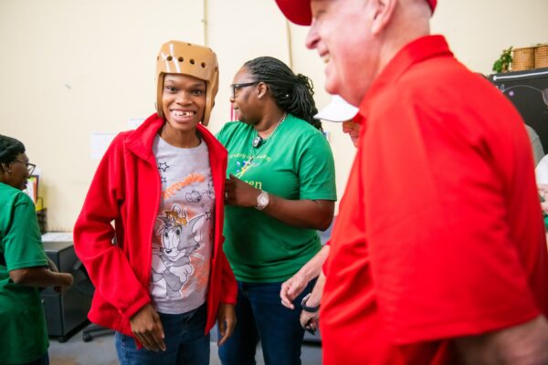 Individual served by Evergreen is seen smiling with Evergreen staff and representatives from the Giving Machine 
