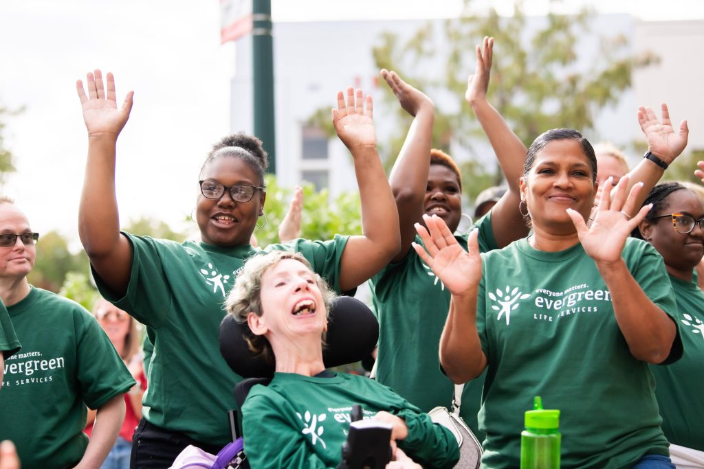 People wearing green Evergreen Life Services with a disabled individual in a wheelchair