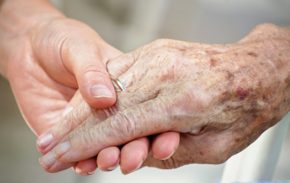 A young person's hand holding an older person's hand