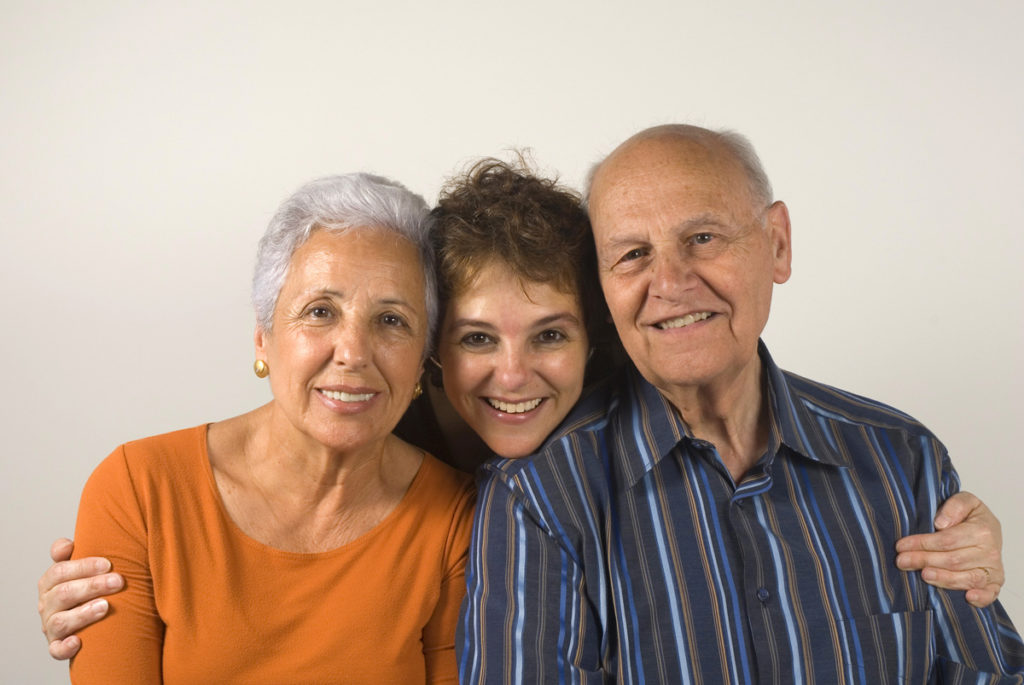 An older woman and man with a younger woman between them, her arms are around the 2 older people